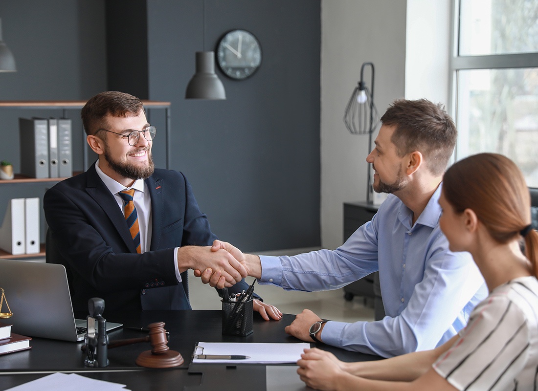 Contact - Friendly Agent Shakes Hands With a Couple in His Office